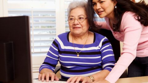 young woman helping elderly woman at the computer